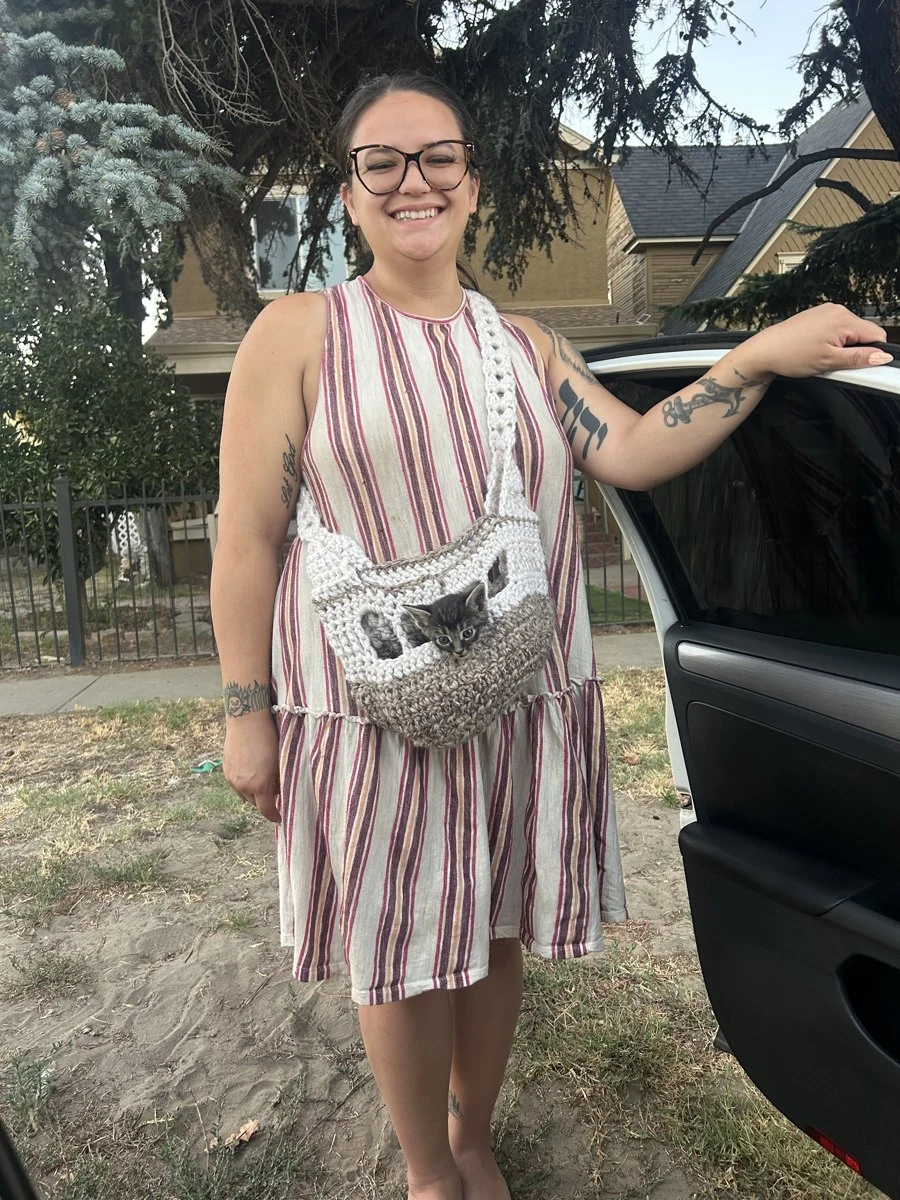 Mercedes wearing her gray and white crochet cat bag outdoors